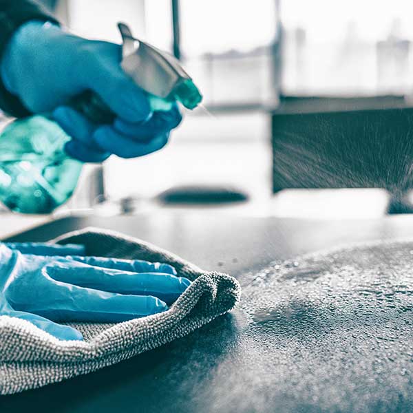 Cleaning home table sanitizing kitchen table surface with disinfectant spray bottle washing surfaces with towel and gloves. COVID-19 prevention sanitizing inside