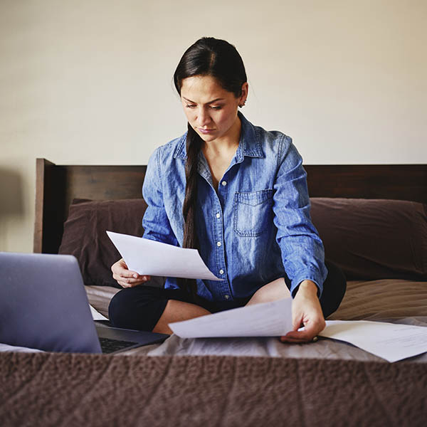 A woman sitting on her bed in a home working with medical matters.