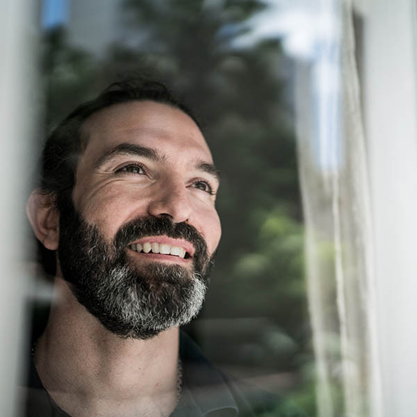 Mature man looking through window at home